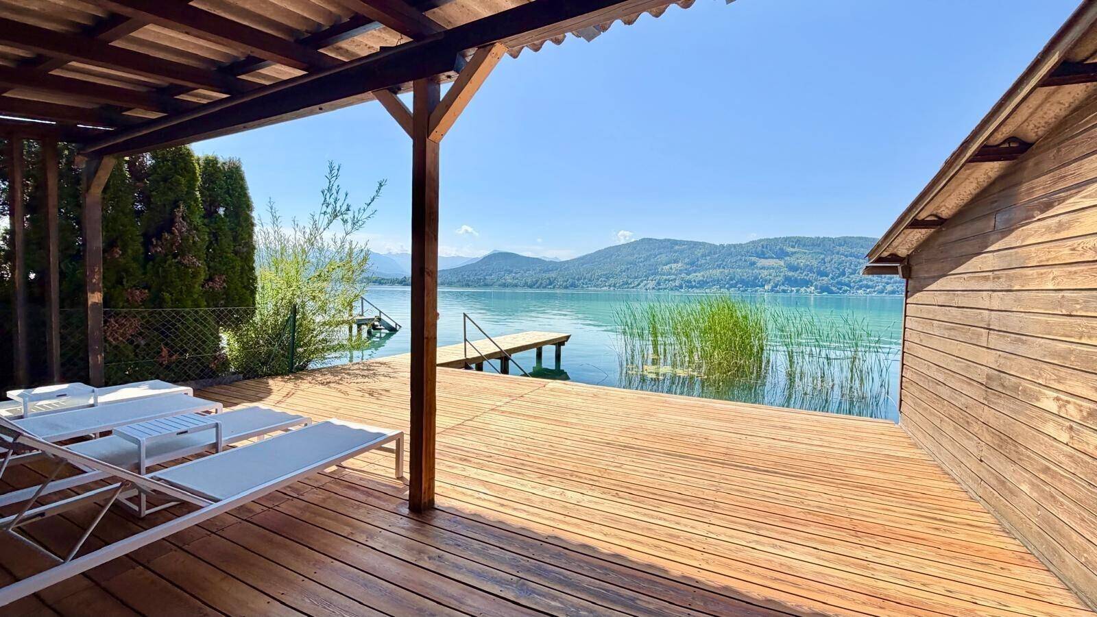 Überdachte Holzterrasse mit Liegestühlen bietet Entspannung direkt am Seeufer.