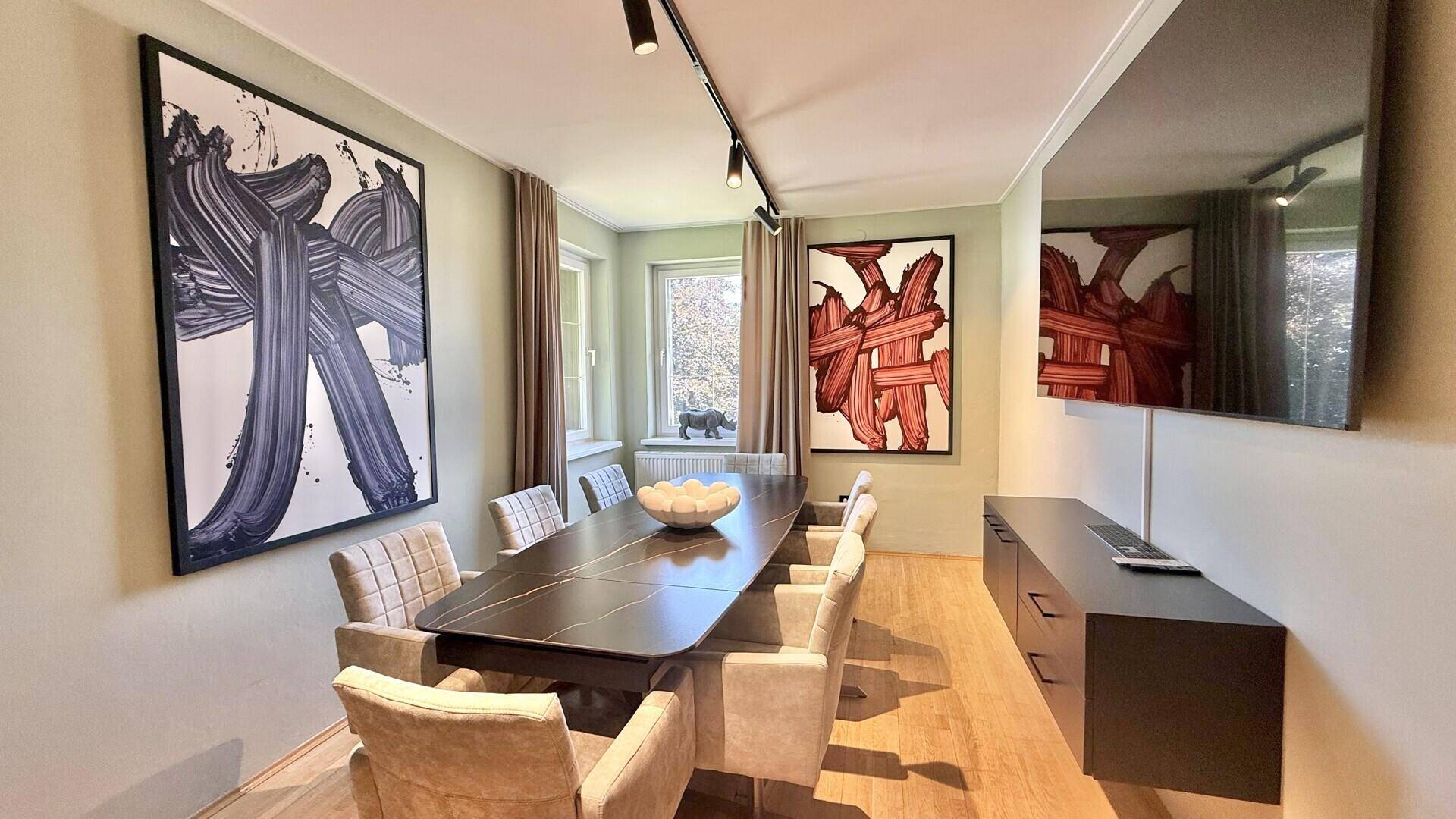 Eleganter Essbereich mit großem Esstisch, bequemen Stühlen und moderner Kunst an den Wänden.