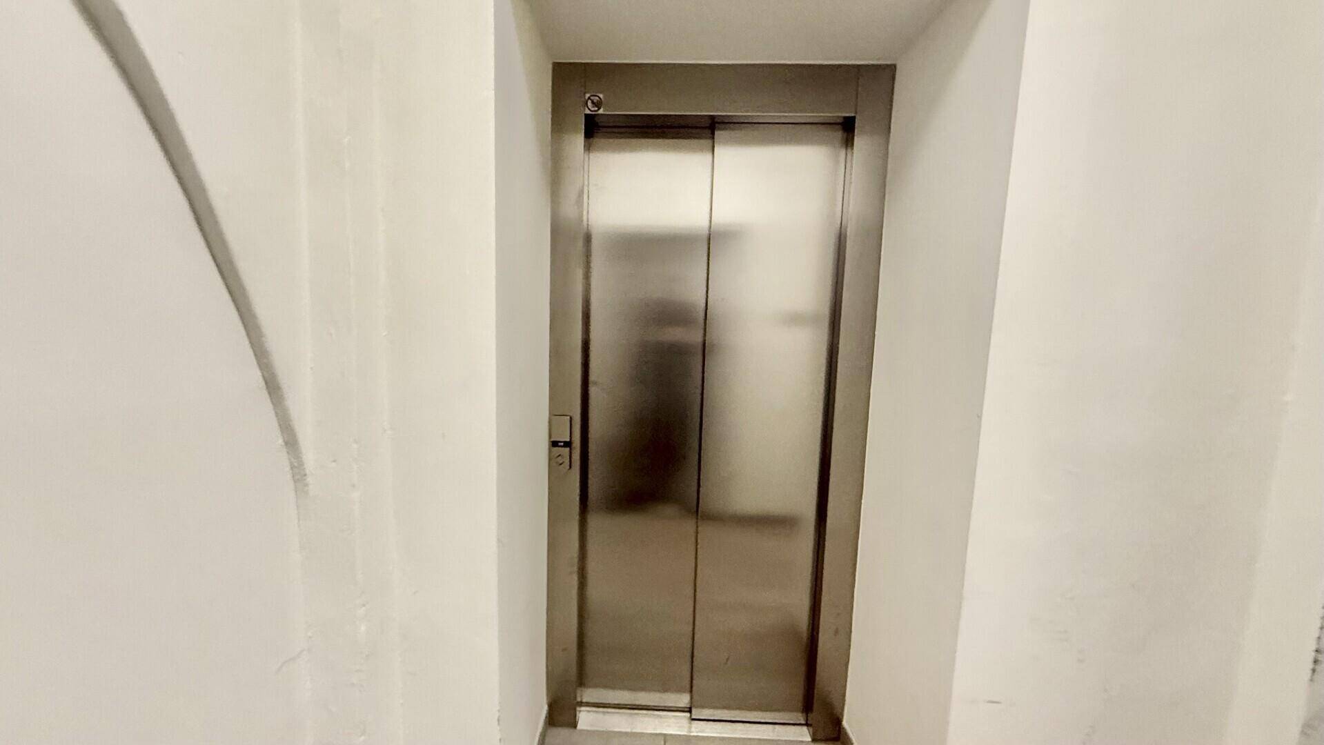 Moderner Aufzug mit Edelstahltüren im Treppenhaus des Gebäudes, bietet bequemen Zugang zu allen Etagen.
