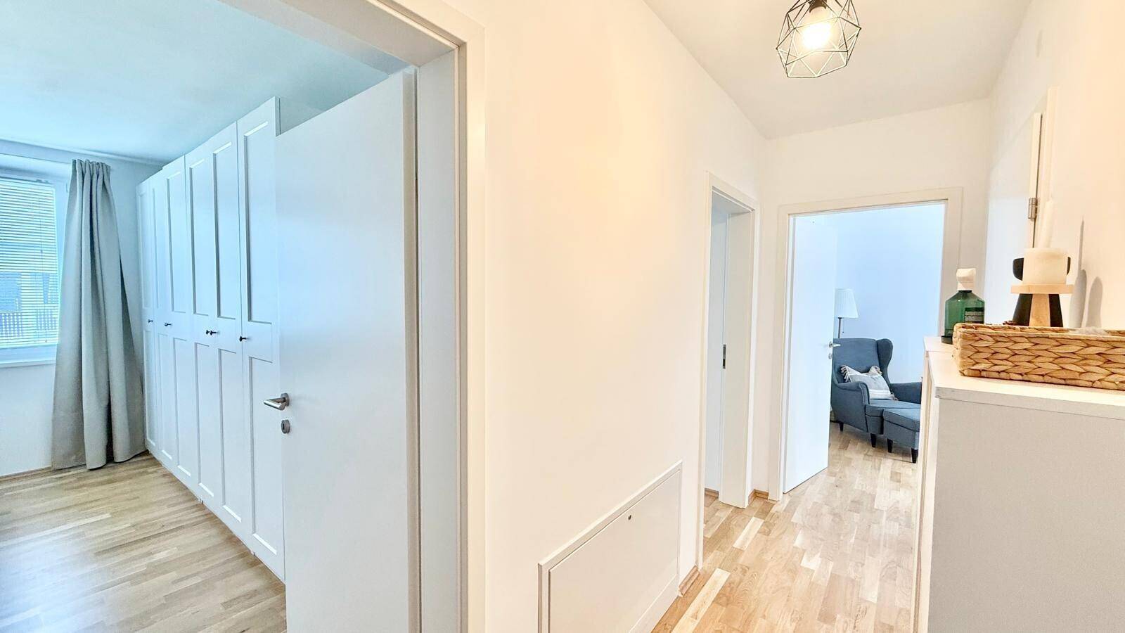 Heller Flur mit Holzboden und Zugang zu verschiedenen Zimmern der Wohnung.