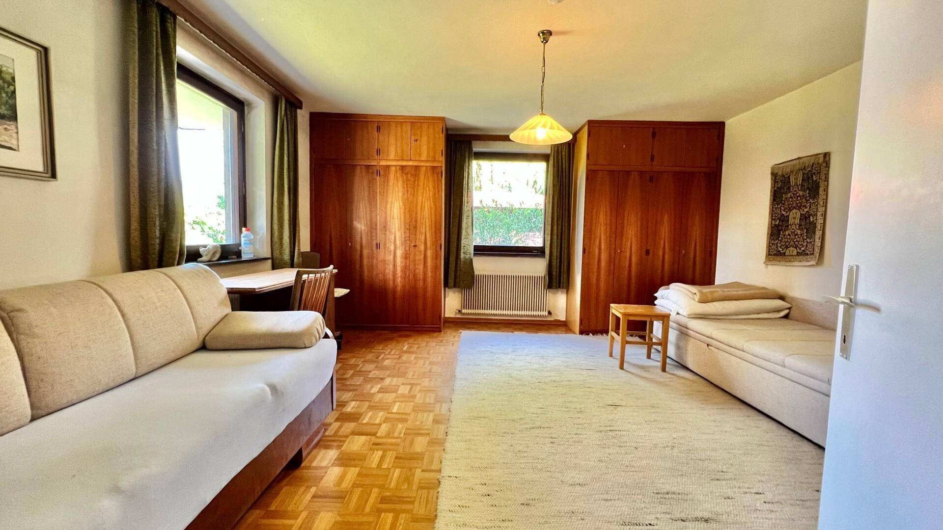 Geräumiges Schlafzimmer mit Parkettboden, Einbauschränken und zwei Fenstern.