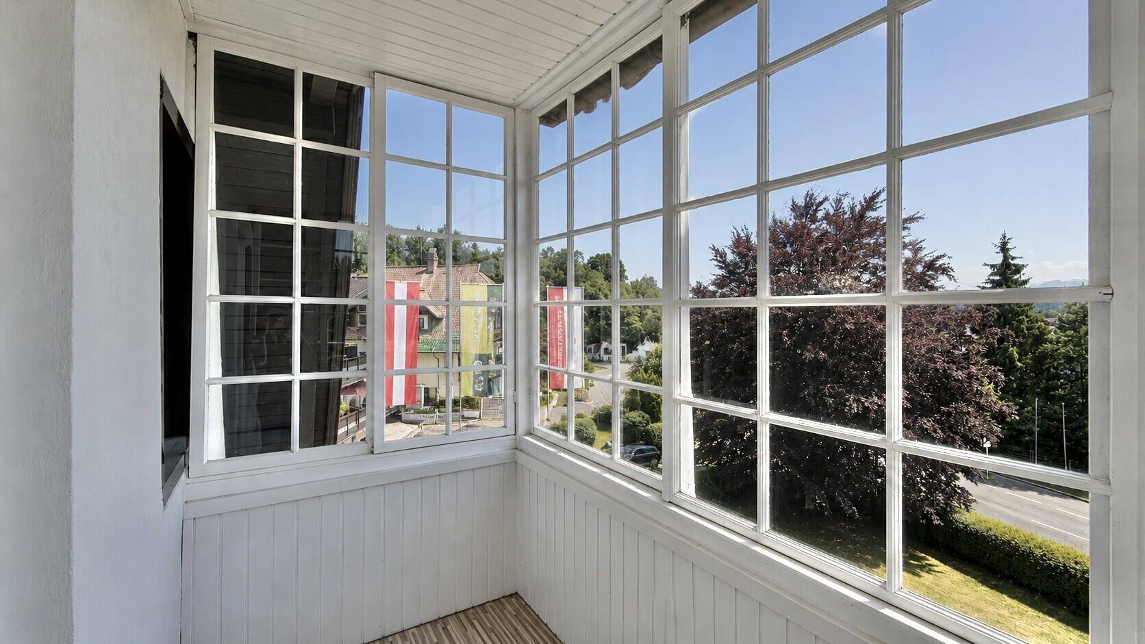 Verglaster Balkon mit vielen Fenstern, die einen weiten Blick auf die Umgebung ermöglichen.