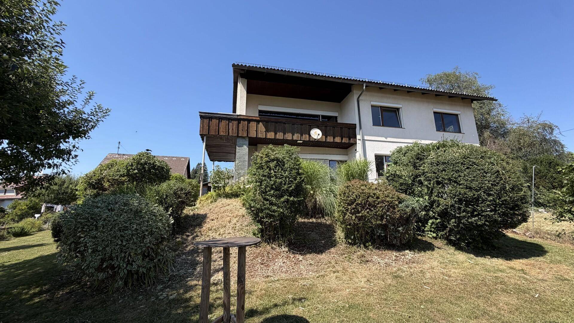 Das Haus mit seinem Gartenbereich und Balkon an einem sonnigen Tag.
