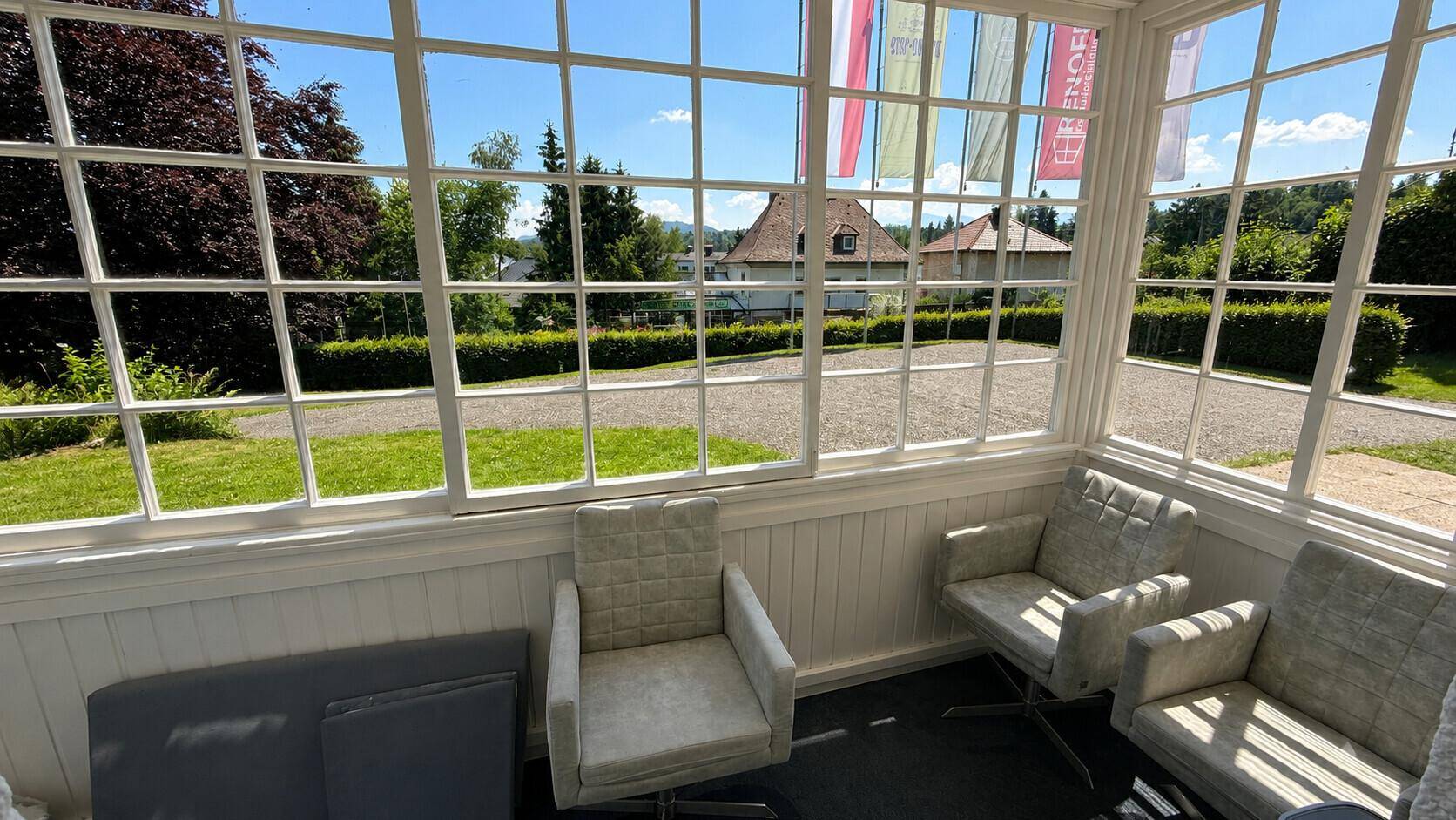 Verglaster Balkon mit bequemen Sesseln und weitem Blick auf die grüne Umgebung.