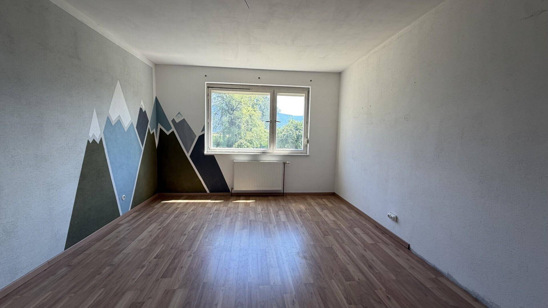 Schlafzimmer mit Holzboden und kreativer Bergwandmalerei.