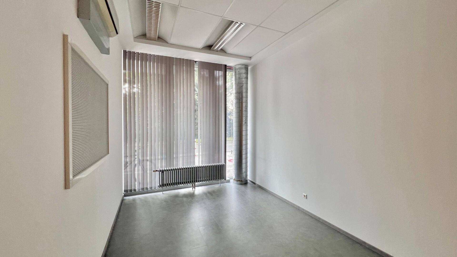Helles Büro mit vertikalen Jalousien, Heizkörper und Klimaanlage an der Wand, bereit zur Einrichtung.
