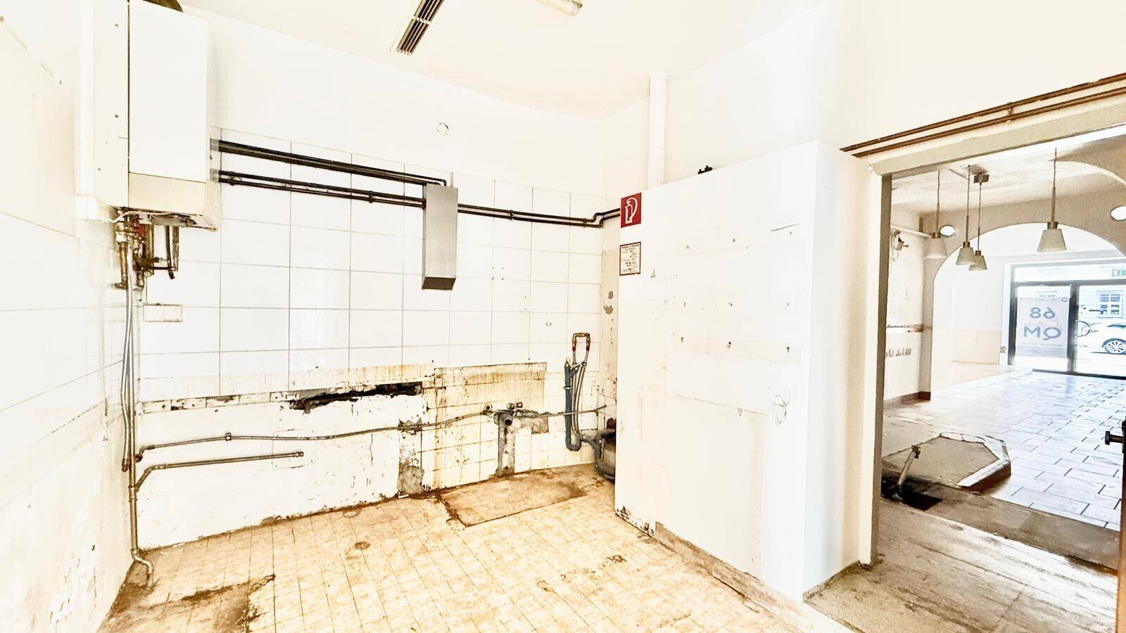 Küche in Renovierung mit gefliesten Wänden, sichtbaren Rohren und einem Warmwasserbereiter.
