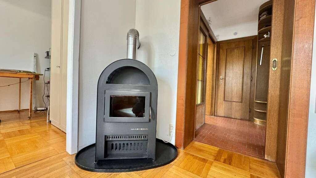 Gemütlicher Holzofen im Wohnbereich mit Parkettboden und Zugang zu weiteren Räumen.