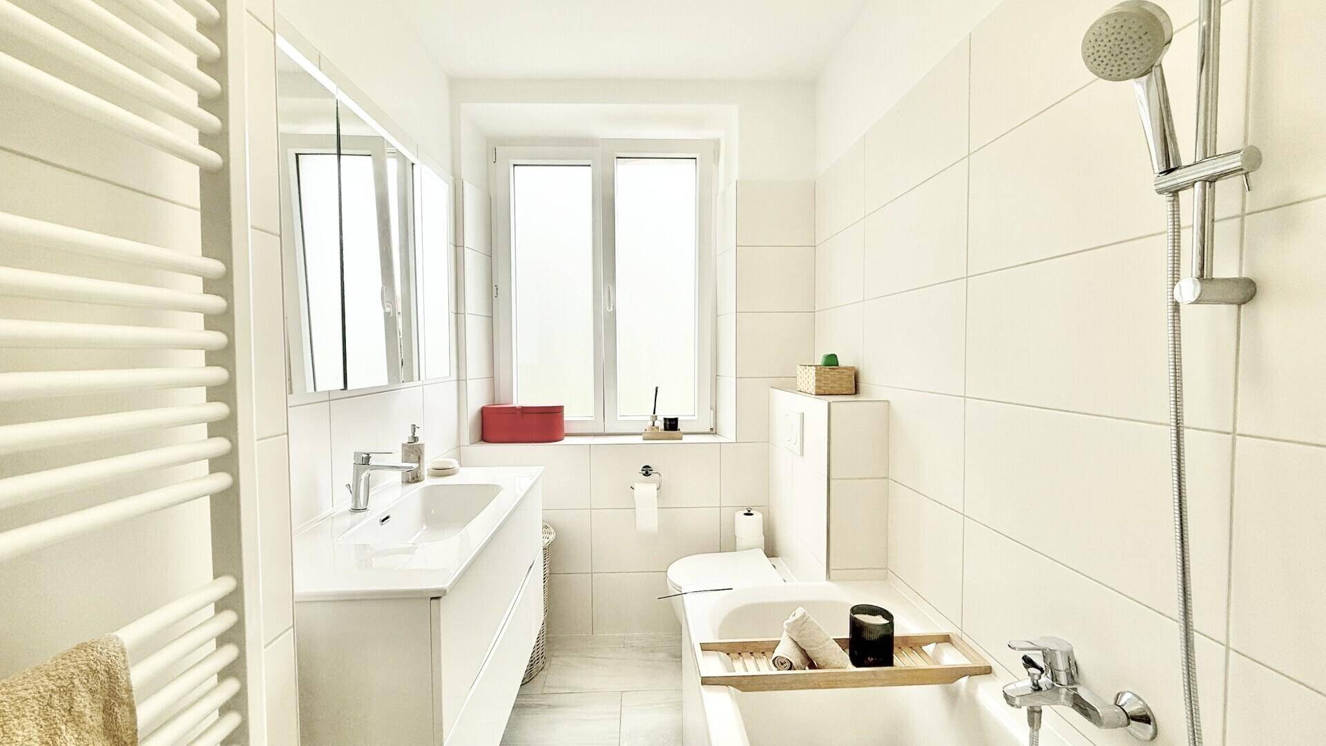 Modernes Badezimmer mit Badewanne, Waschbecken, WC und Fenster.