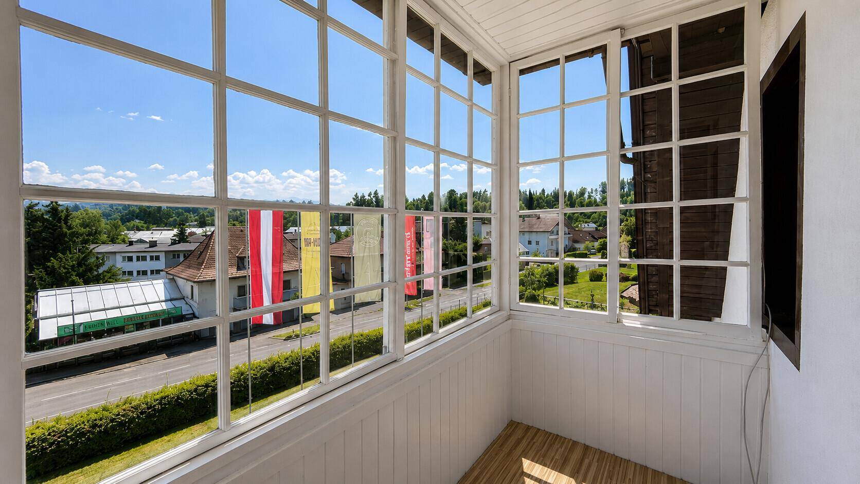 Heller, verglaster Balkon mit Panoramablick auf die Stadt und die umliegende Landschaft.