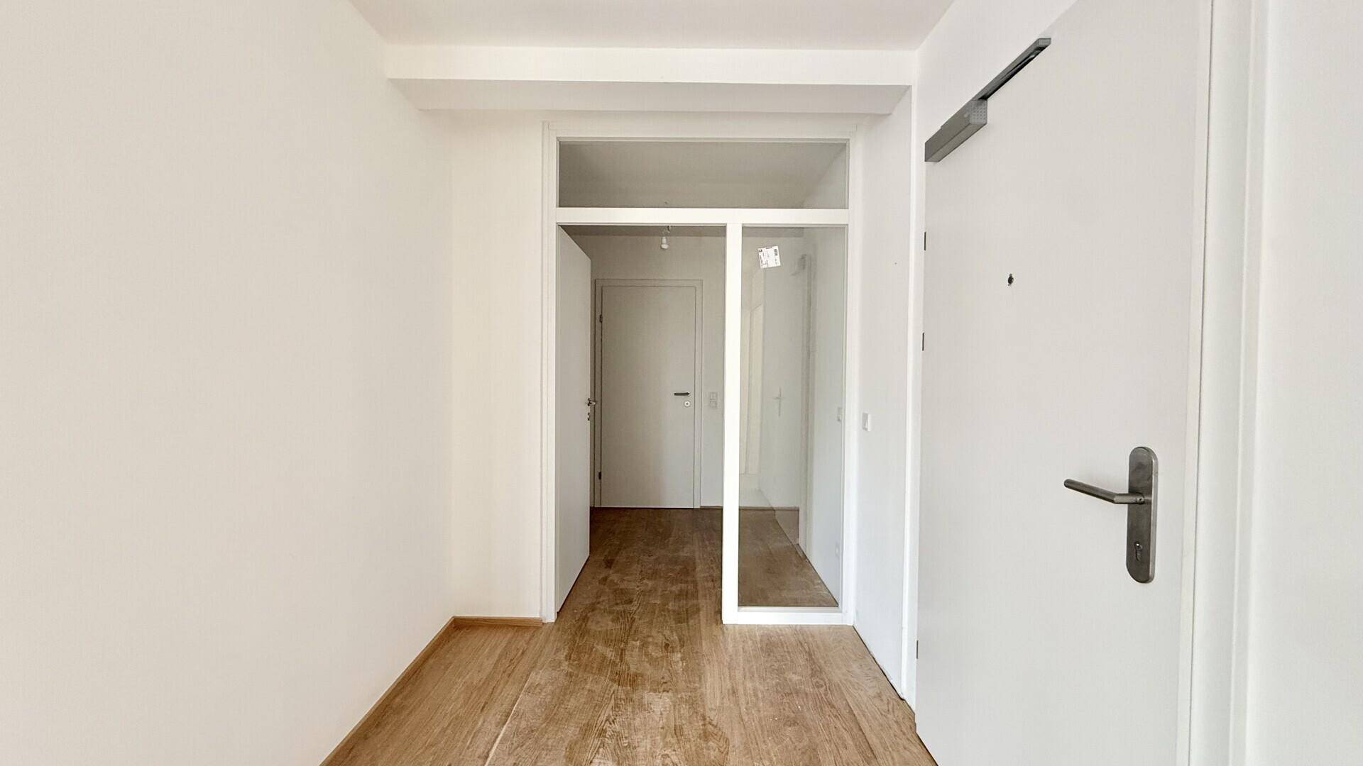 Heller Eingangsbereich mit Holzboden und weiß gestrichenen Wänden.