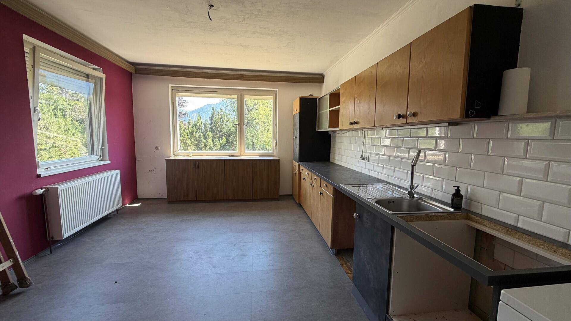 Renovierungsbedürftige Küche mit alten Holzschränken und rosa Wänden.