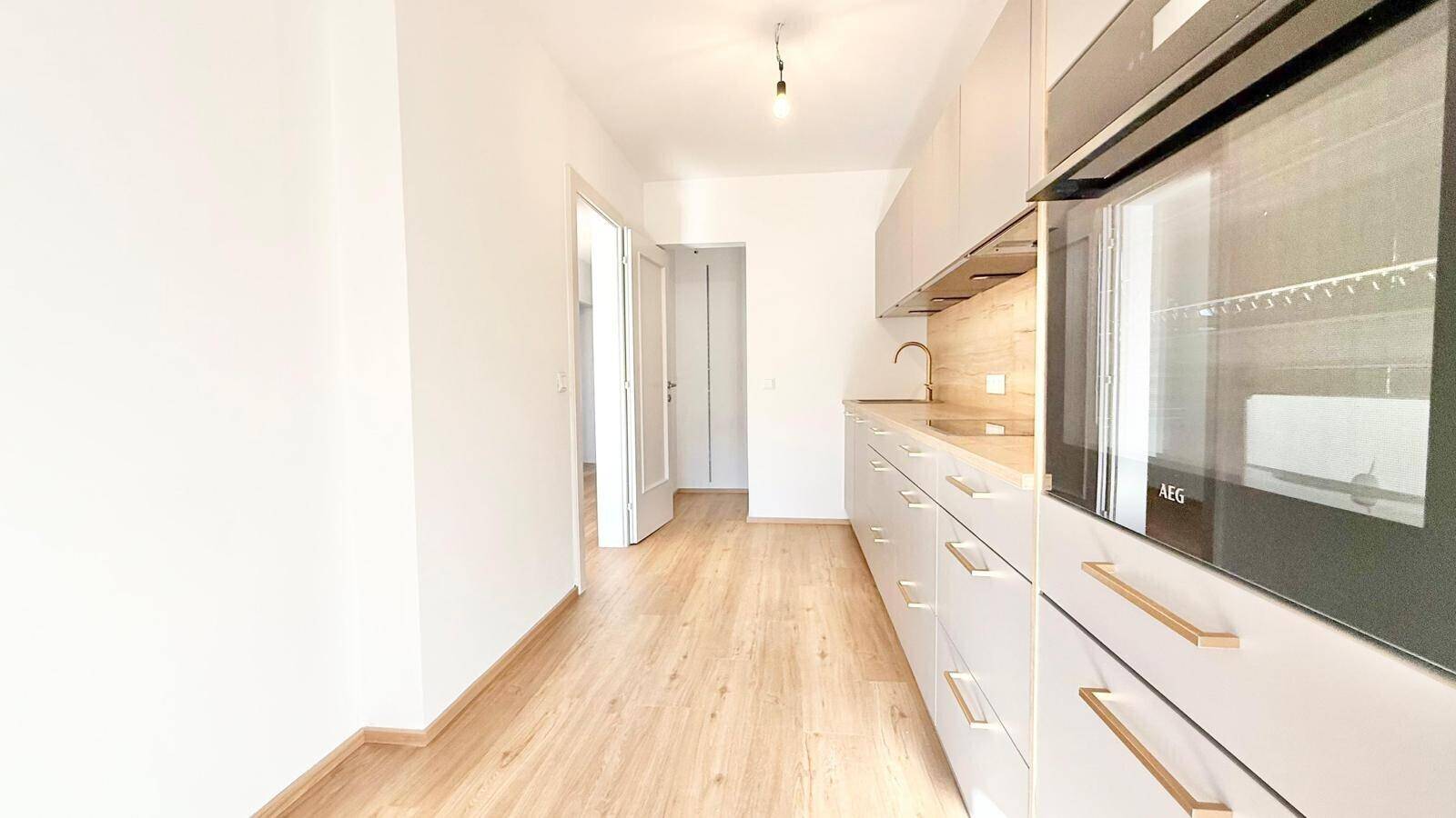 Helle Küche mit modernen grauen Schränken, Holzoptik und integriertem Backofen.