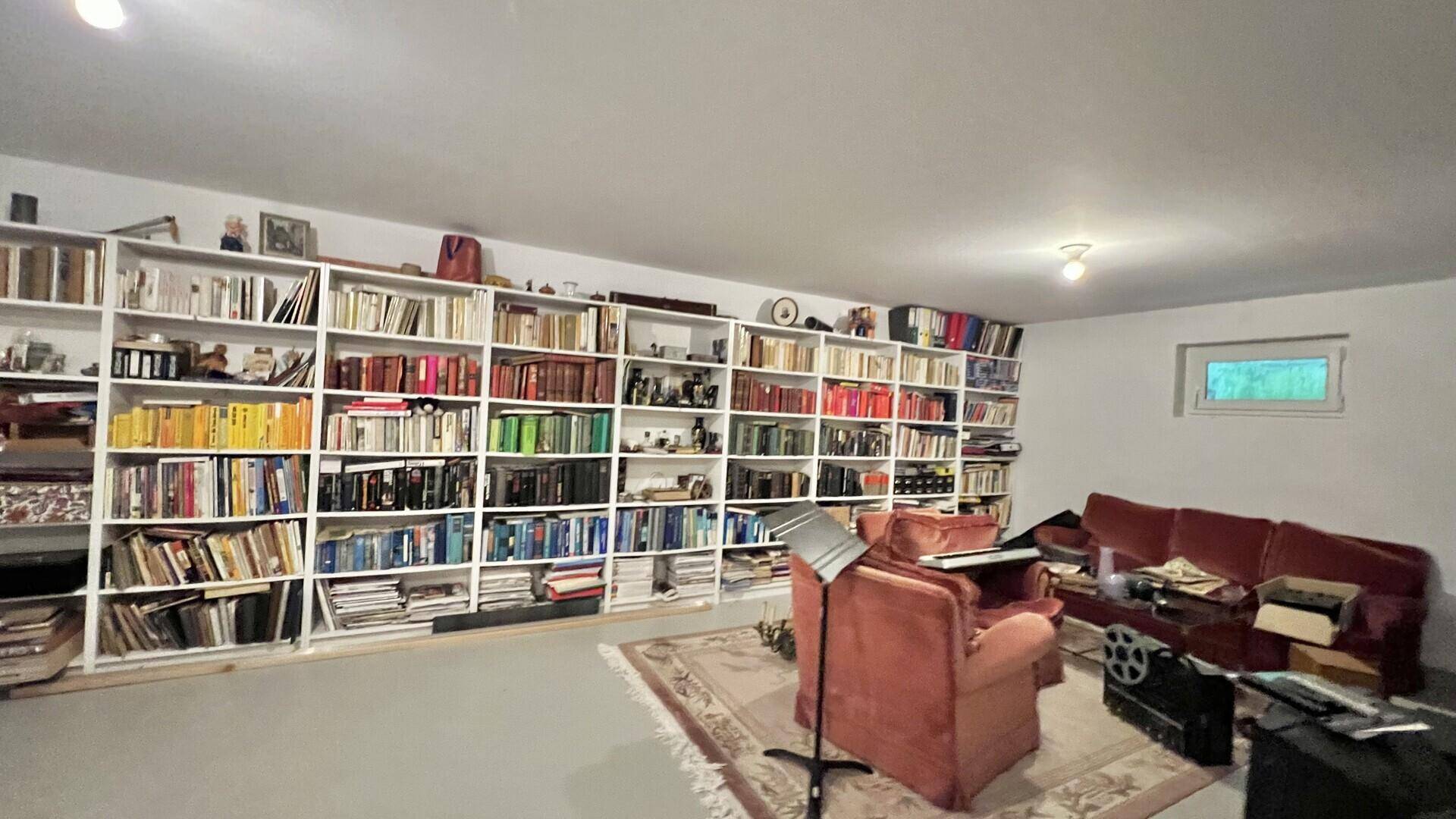Geräumiger Raum mit raumhohen Bücherregalen und gemütlicher Sitzecke.