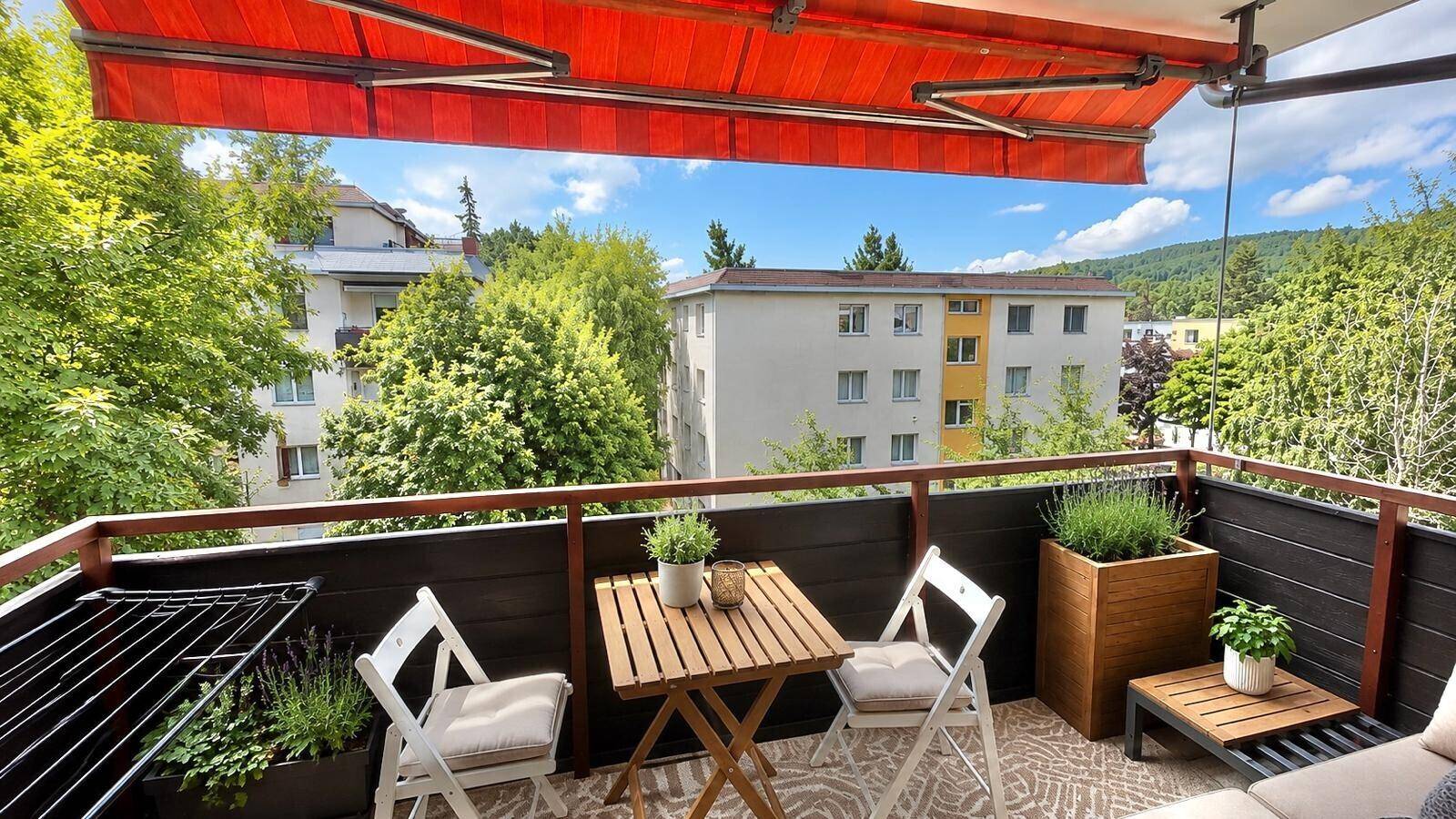 Gemütlicher Balkon mit Markise, Sitzgelegenheiten und Blick ins Grüne.