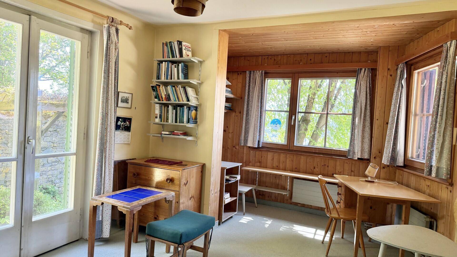 Kleiner, holzvertäfelter Raum mit Fenster und Zugang zum Außenbereich, ideal als Arbeitszimmer.