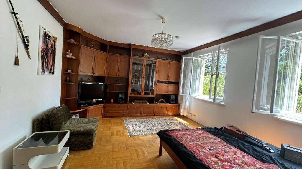 Geräumiges Wohnzimmer mit Holzparkett, Einbauschränken und viel Tageslicht.