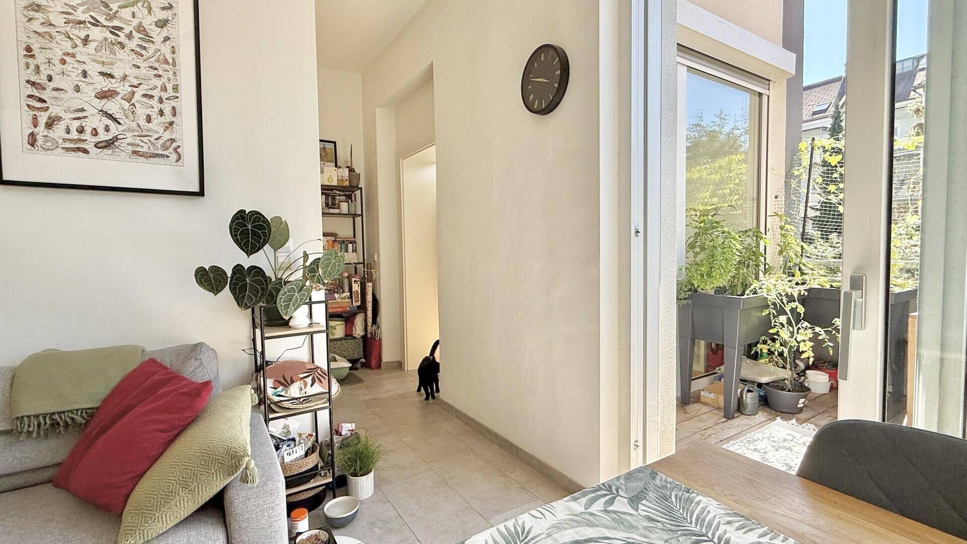 Gemütlicher Wohnbereich mit Sofa, Blick auf den Balkon und Zugang zu einem hellen Flur.