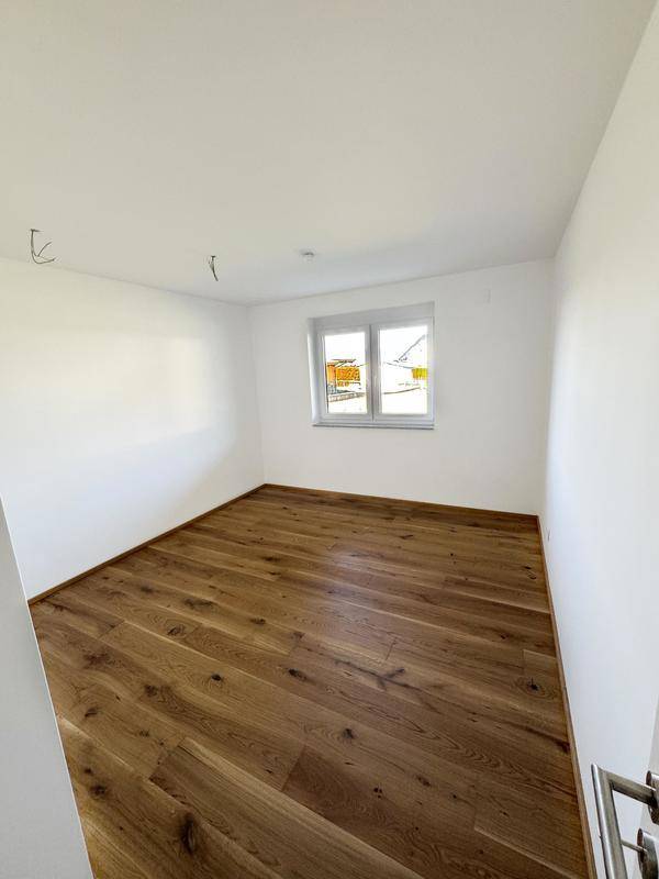 Kleiner, heller Raum mit Holzboden und Fenster, ideal als Kinder- oder Arbeitszimmer.