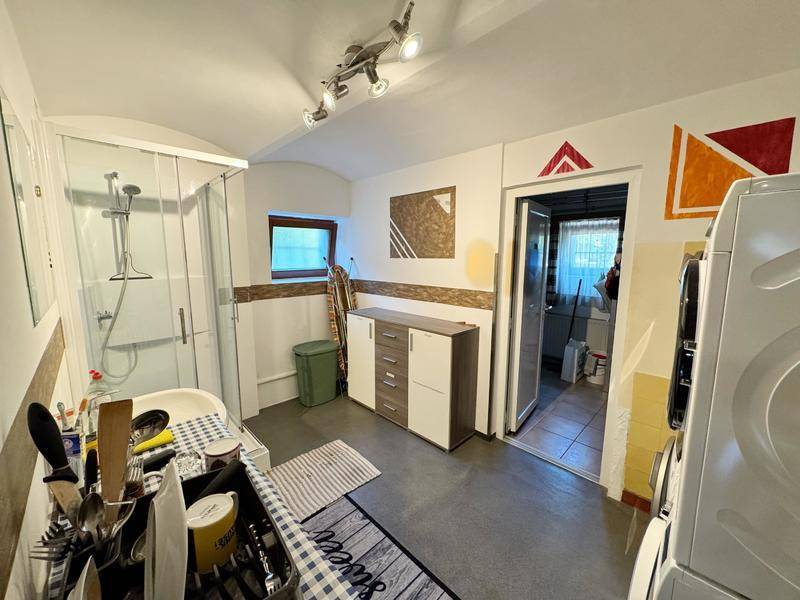 Funktionales Badezimmer mit Duschkabine, Waschbecken und Platz für Waschmaschinen.