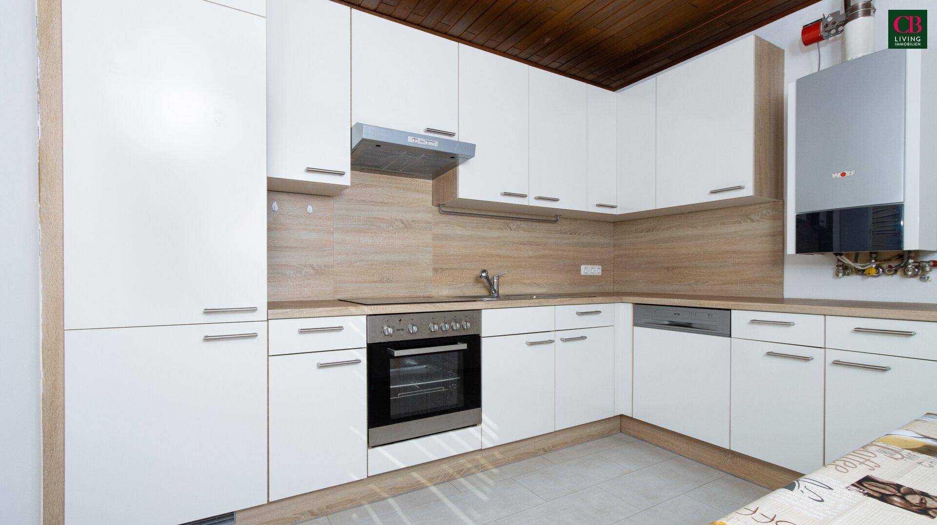 Moderne Einbauküche mit weißen Fronten, integrierten Geräten und Holzdecke.