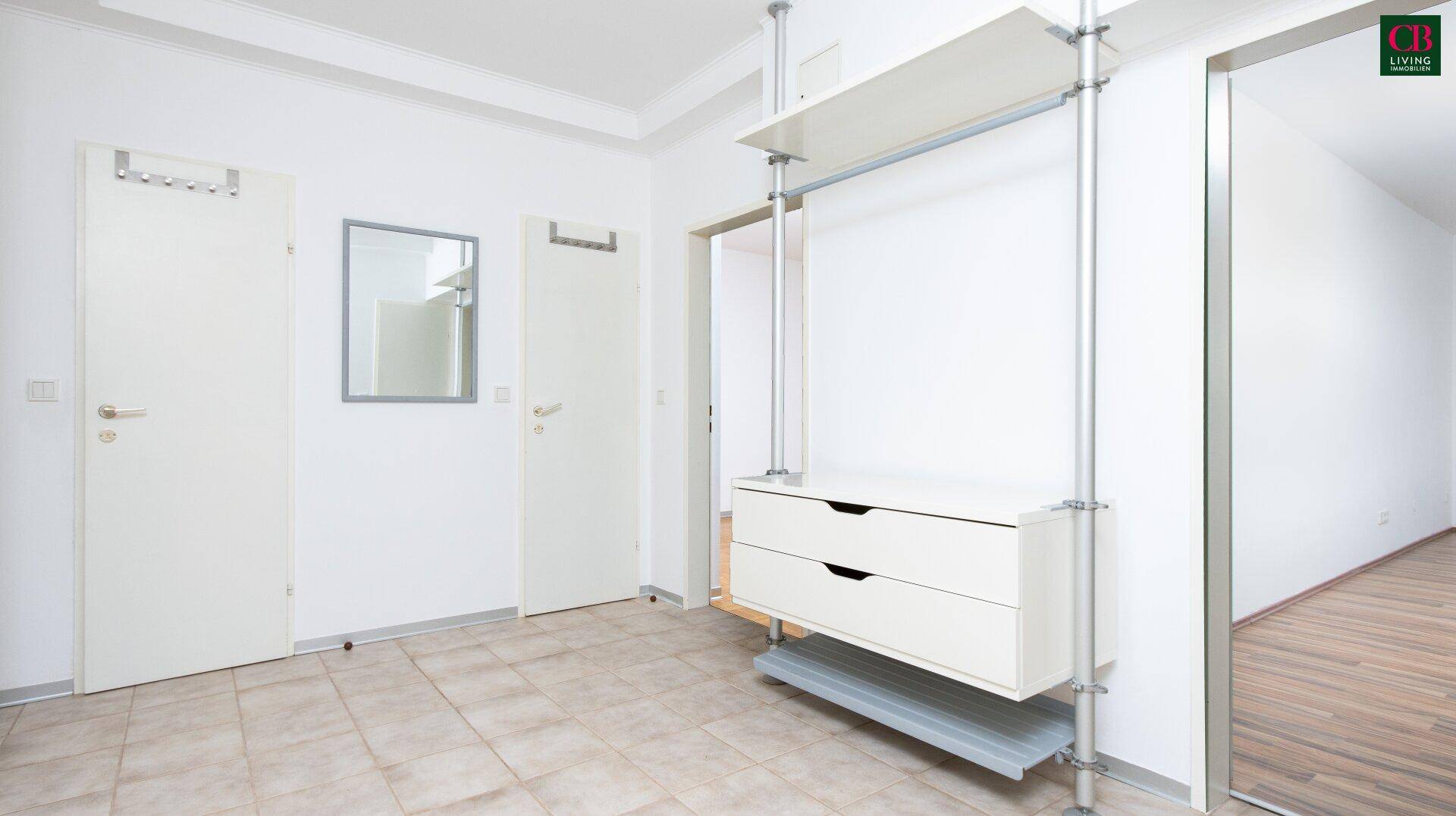 Heller Flur mit Fliesenboden und offenem Garderobensystem.