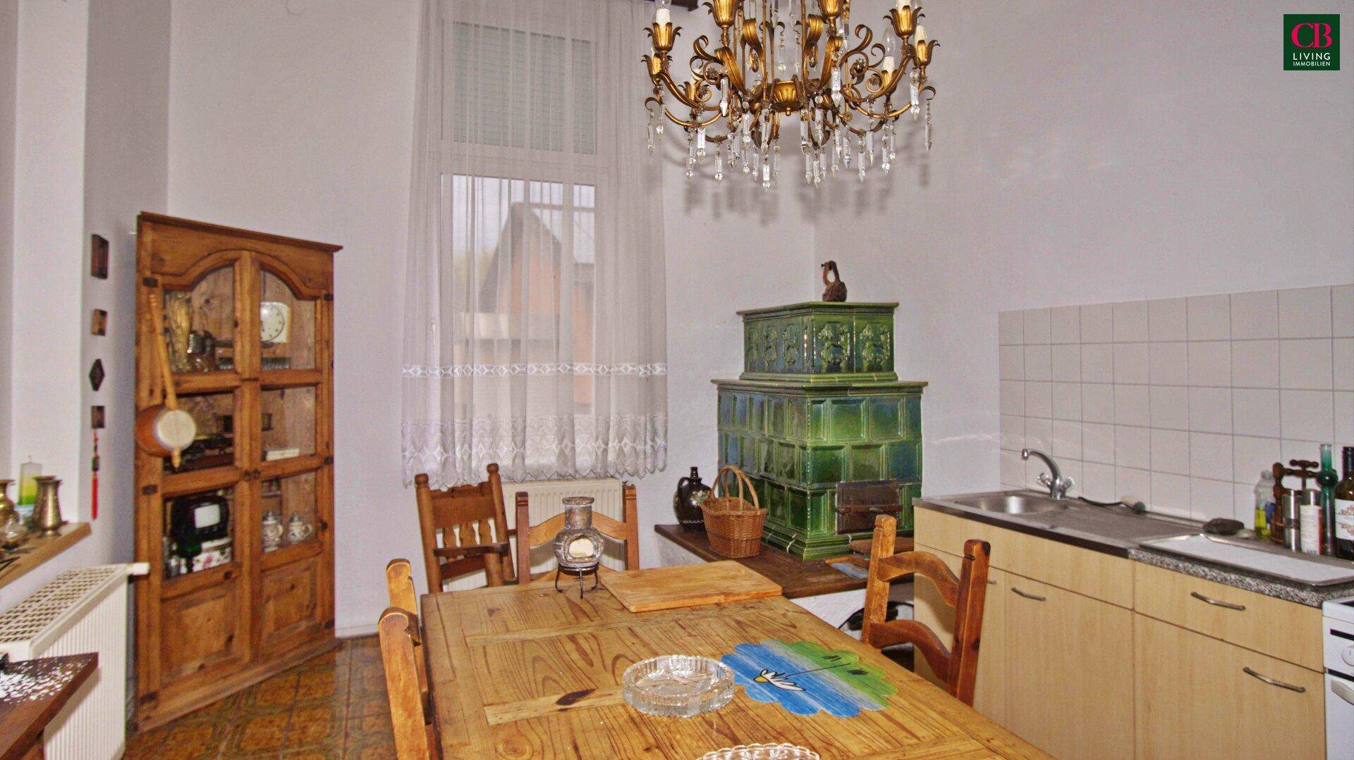 Küche mit traditionellem Kachelofen, Holztisch und einfacher Küchenzeile.