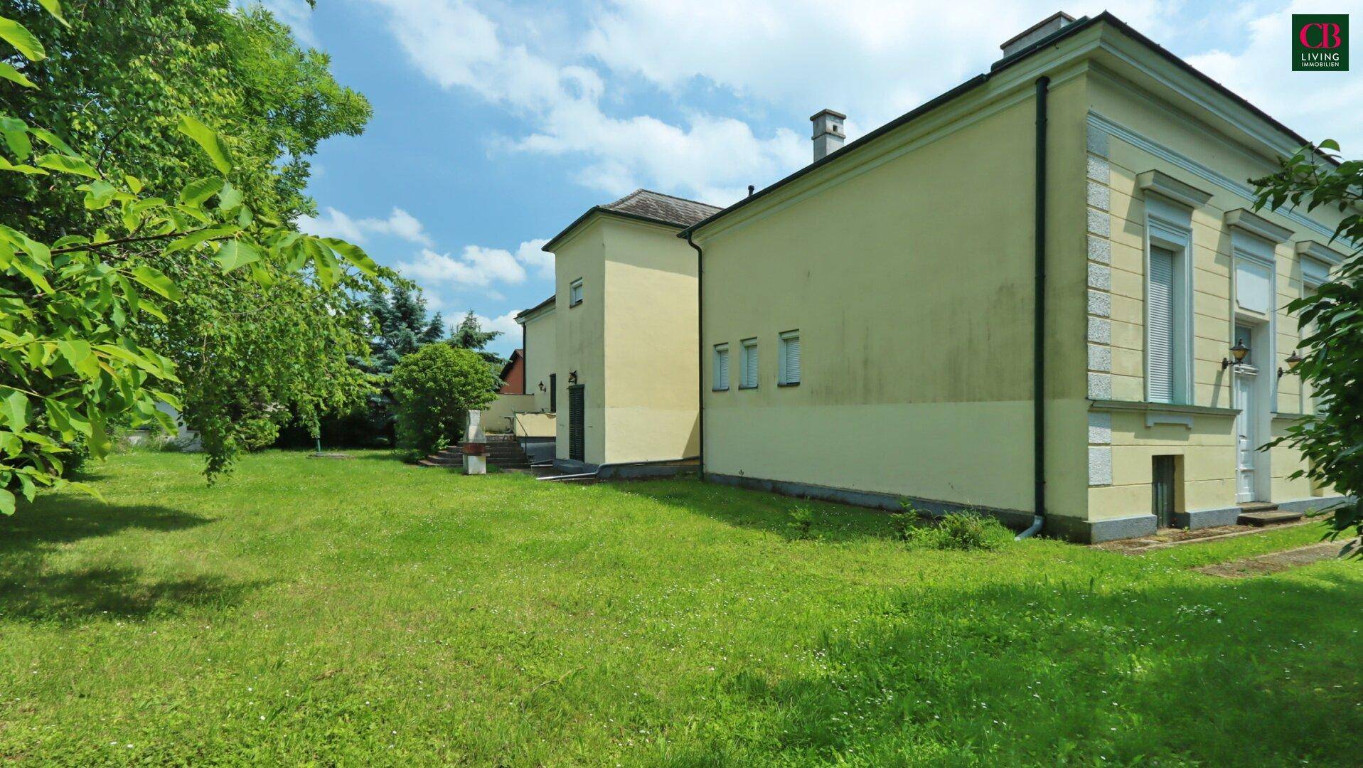 Großer, gepflegter Rasenbereich neben dem historischen Gebäude unter blauem Himmel.