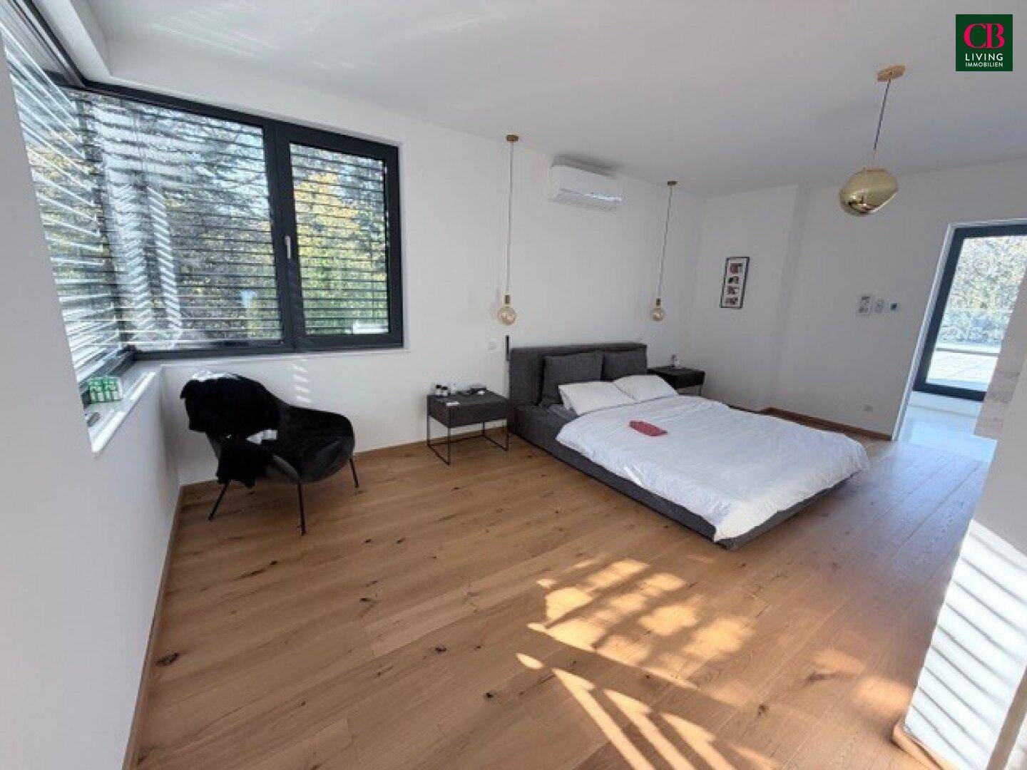 Helles Schlafzimmer mit Holzboden, großem Fenster und modernem Bett, das zum Entspannen einlädt.