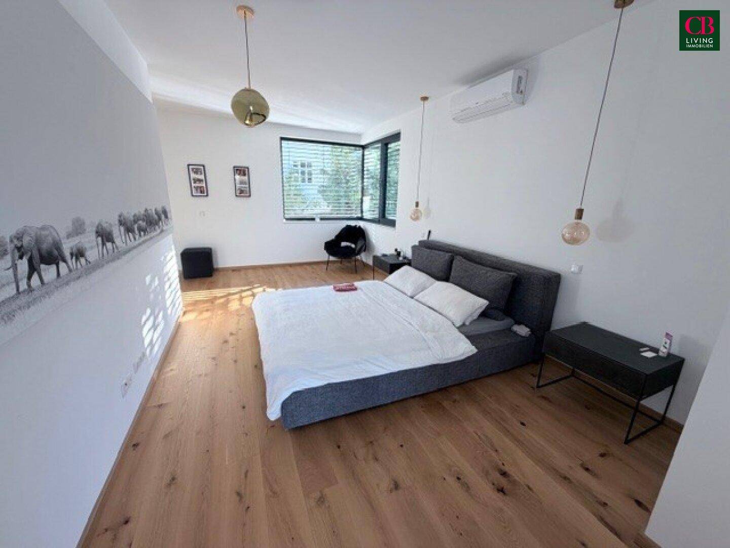 Geräumiges Schlafzimmer mit Holzboden, großem Fenster und Klimaanlage für angenehme Nächte.