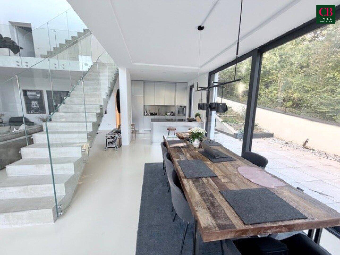 Eleganter Essbereich mit großem Holztisch und Blick auf die Terrasse, integriert in den offenen Wohnraum.