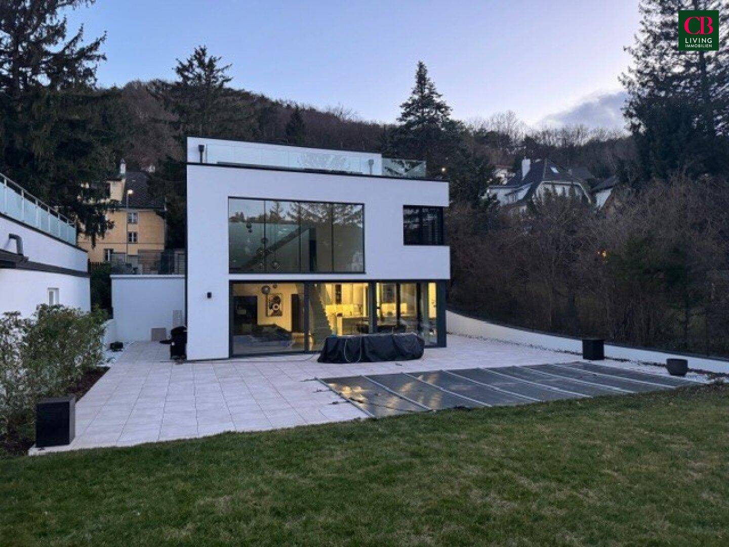 Moderne Villa bei Dämmerung mit beleuchtetem Pool und Garten, der zum Entspannen einlädt.