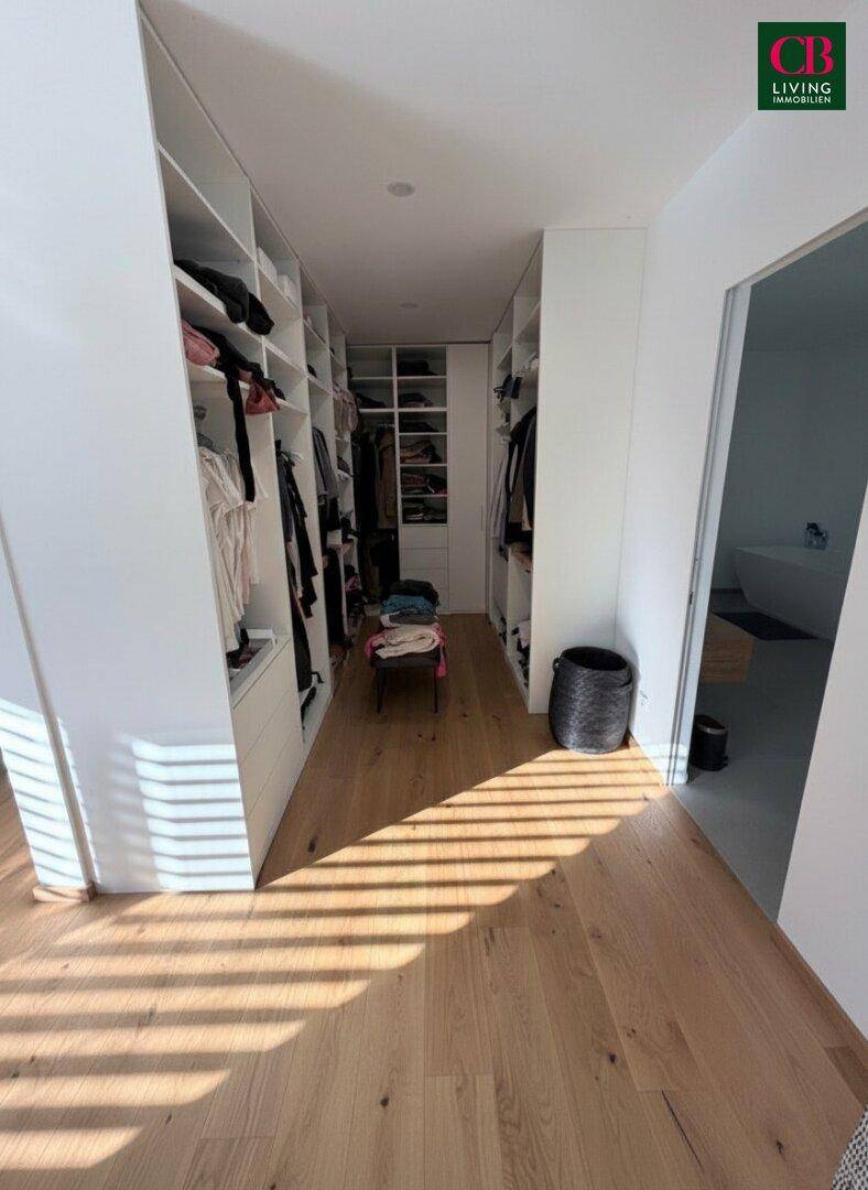 Praktischer begehbarer Kleiderschrank mit viel Stauraum und Holzboden, direkt neben dem Schlafzimmer.