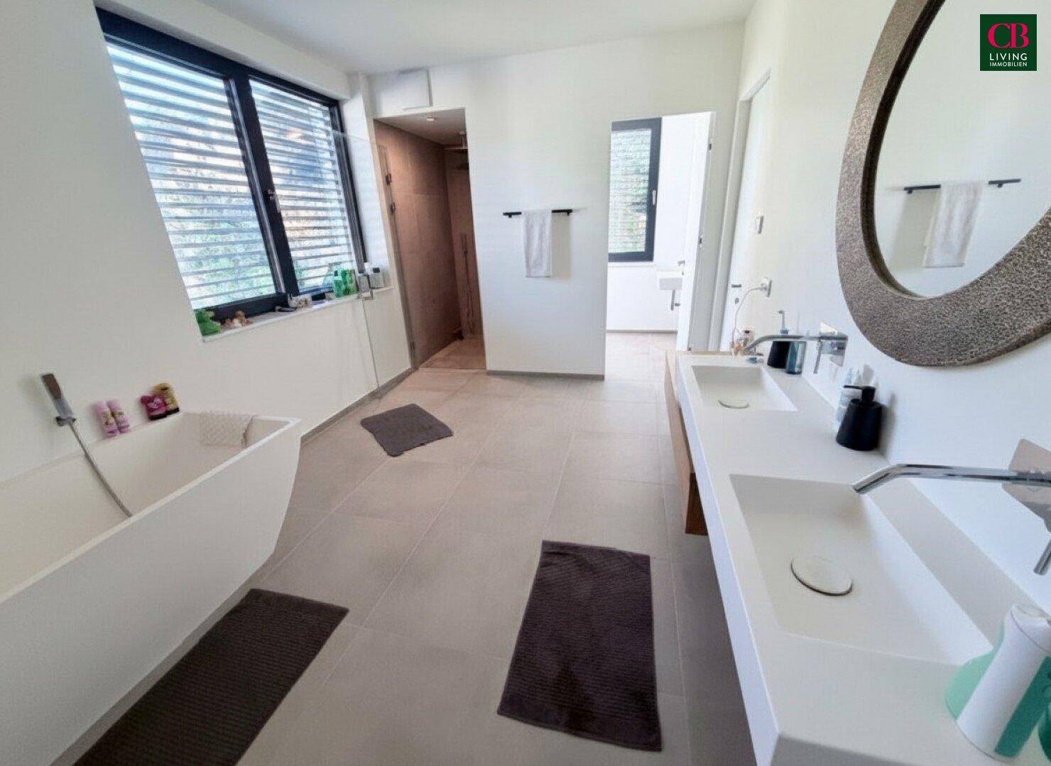 Elegantes Badezimmer mit Doppelwaschbecken, freistehender Badewanne und Zugang zu einer Dusche.