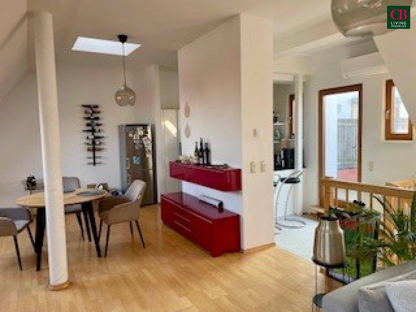 Offener Wohn- und Essbereich im Dachgeschoss mit Holzboden und Zugang zu weiteren Räumen.