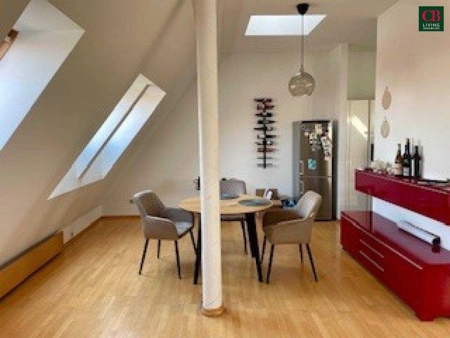 Heller Essbereich im Dachgeschoss mit Holzboden, Esstisch und Dachfenstern.