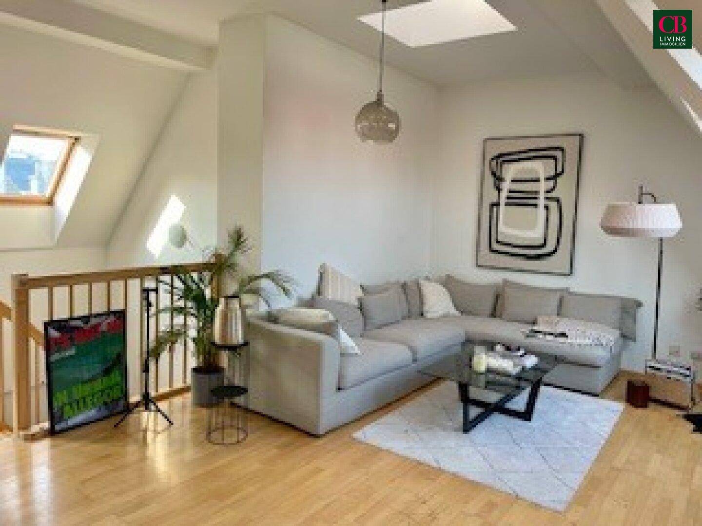 Geräumiges Wohnzimmer im Dachgeschoss mit hellem Holzboden und moderner Einrichtung.