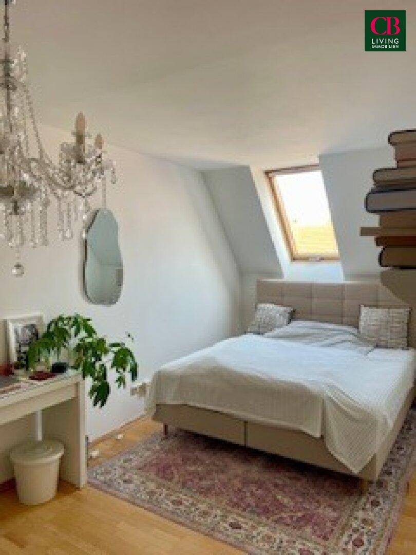 Helles Schlafzimmer im Dachgeschoss mit Holzboden, Dachfenster und stilvoller Einrichtung.