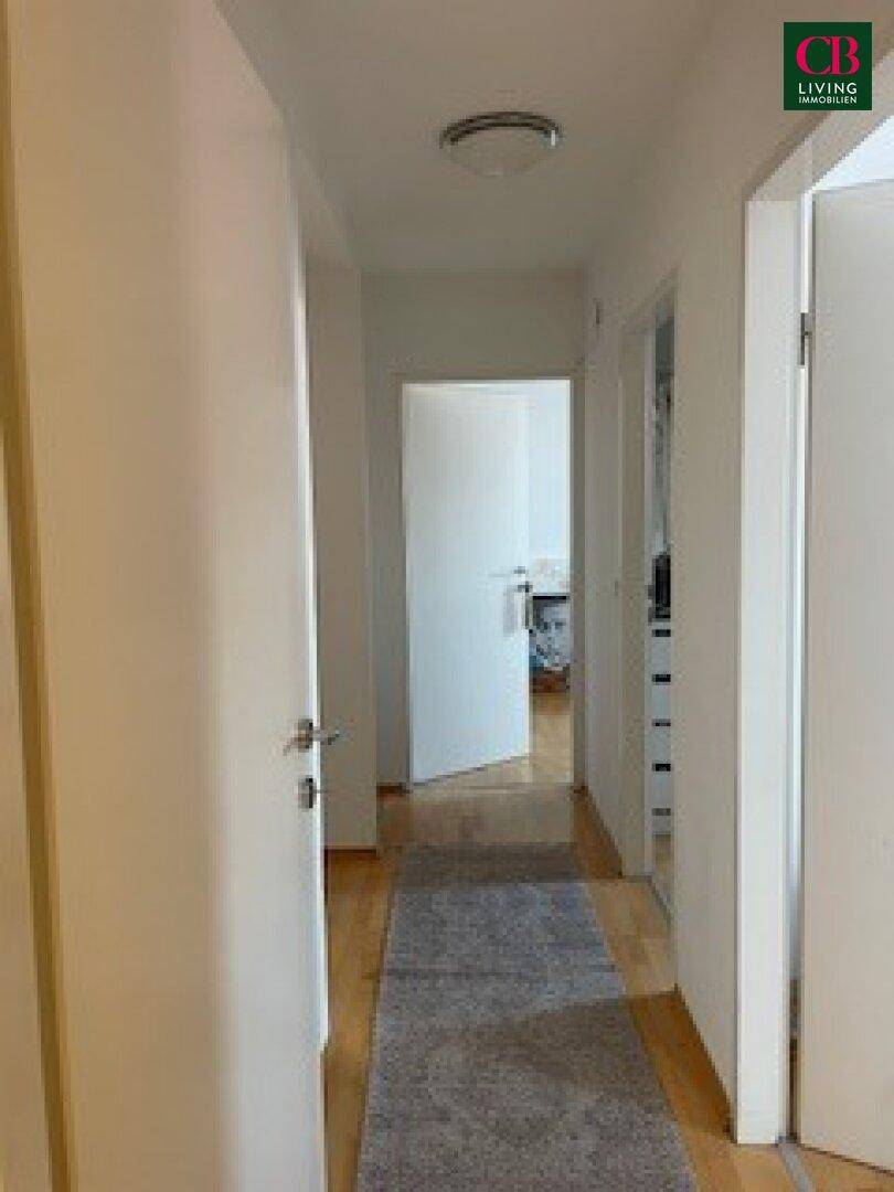 Heller Flur mit Holzboden und Zugang zu verschiedenen Zimmern.