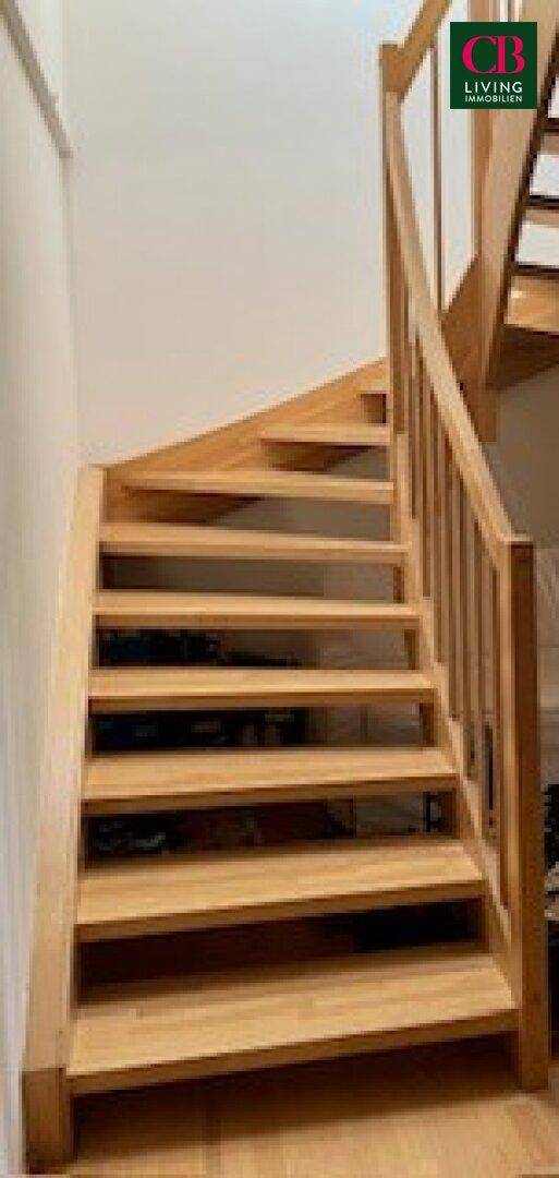 Moderne Holztreppe mit Geländer, die die verschiedenen Ebenen der Wohnung verbindet.