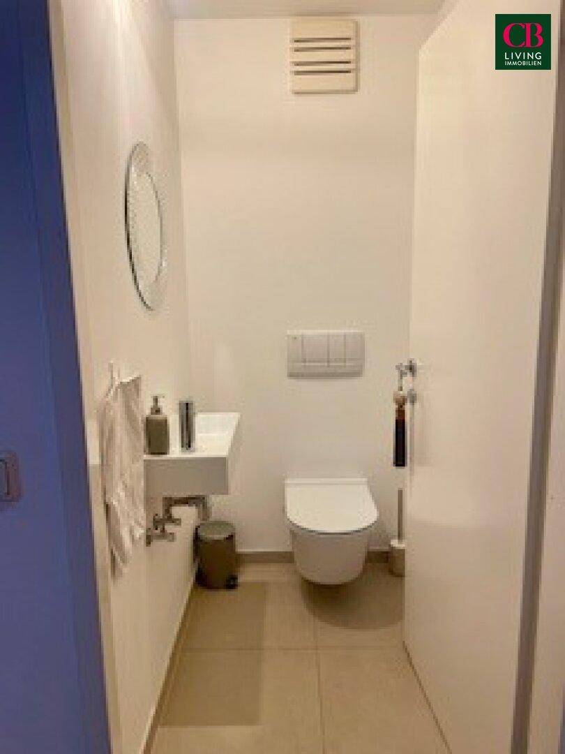 Kleines Gäste-WC mit wandhängendem WC, Waschbecken und Lüftung.