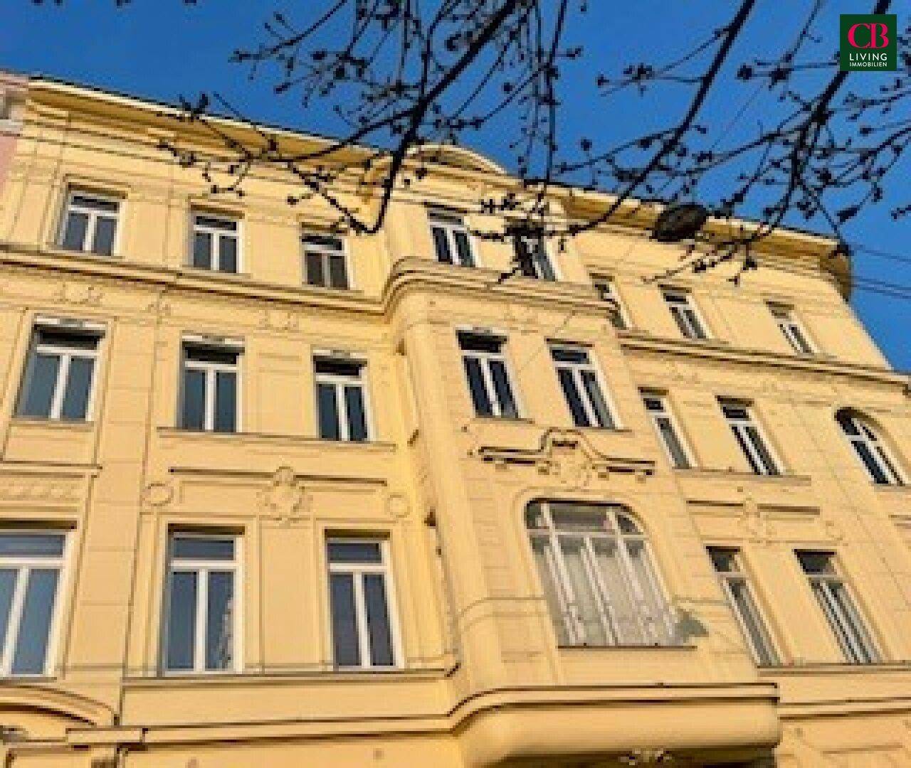 Klassische Fassade eines Altbaus mit vielen Fenstern und architektonischen Details.