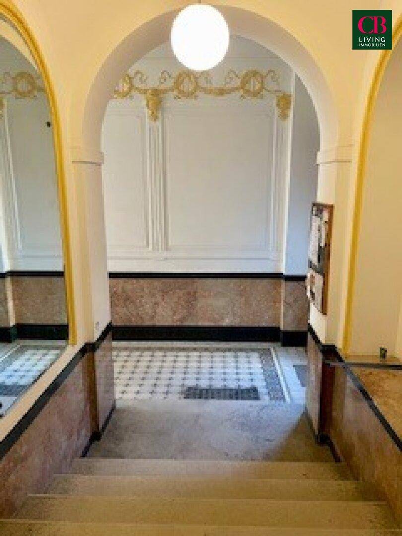 Repräsentativer Eingangsbereich eines Altbaus mit Bögen, Stuck und gemustertem Fliesenboden.