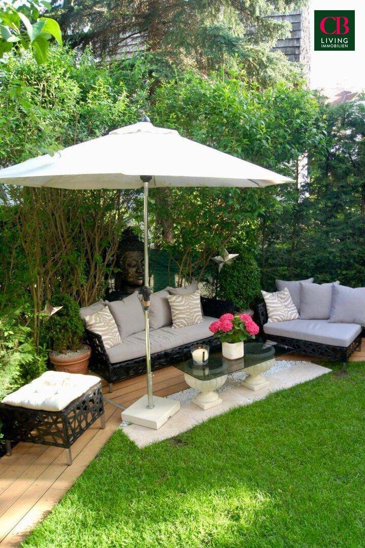 Gemütlicher Gartenbereich mit Sitzgelegenheiten, Sonnenschirm und üppiger Bepflanzung für Entspannung.