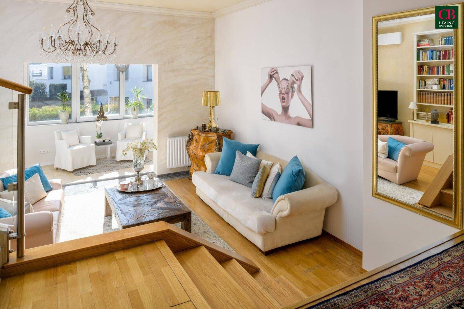 Elegantes Wohnzimmer mit Parkettboden, Treppe und Blick auf den hellen Wintergarten.