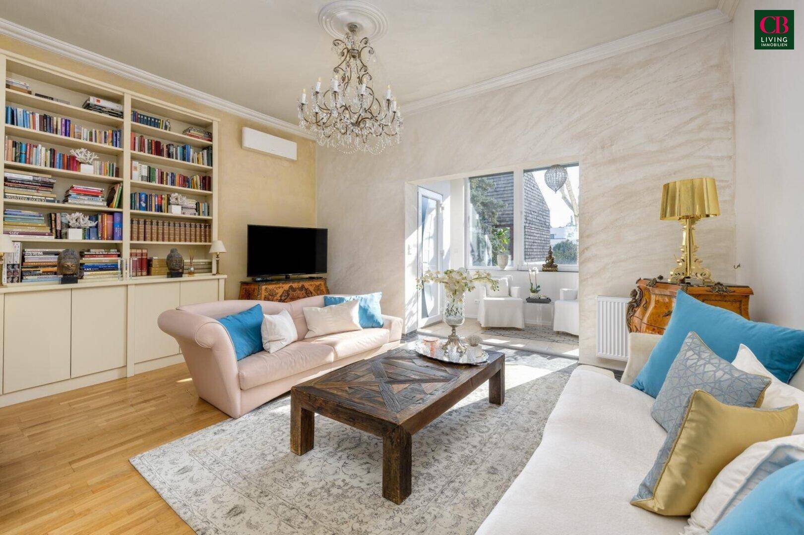 Helles Wohnzimmer mit Parkettboden, großem Teppich und Blick auf den sonnigen Außenbereich.