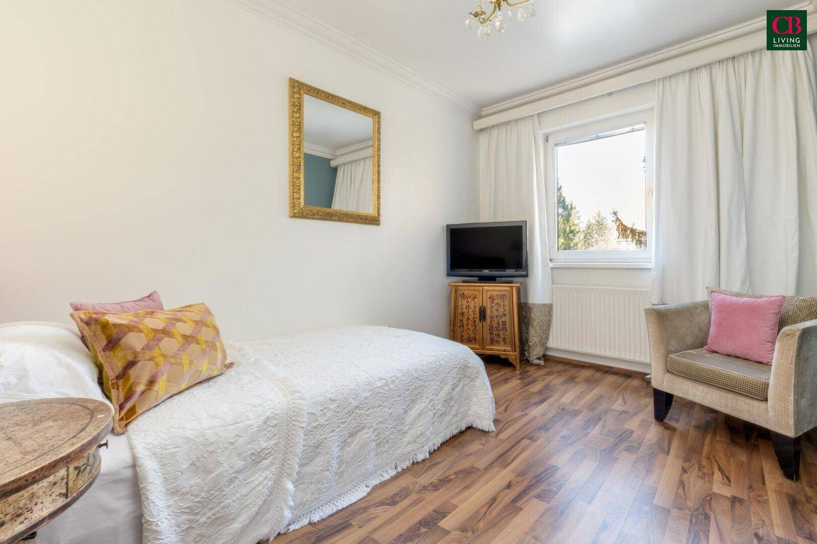 Gemütliches Schlafzimmer mit Holzboden, Einzelbett und Fenster mit Vorhängen.