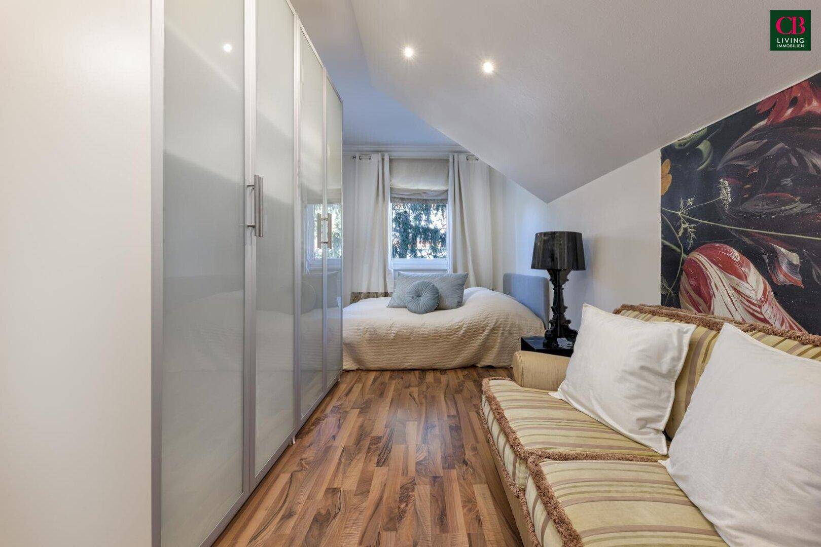 Dachgeschoss-Schlafzimmer mit Schrägen, Laminatboden und integrierten Kleiderschränken.