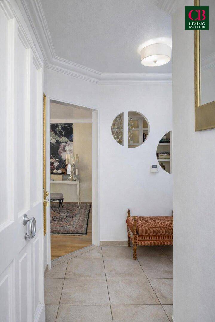 Heller Flur mit Fliesenboden, Spiegel und Zugang zu weiteren Räumen.