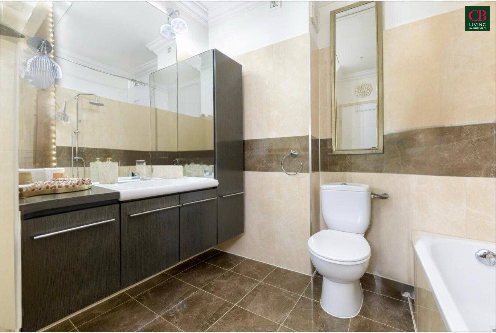 Modernes Badezimmer mit dunklen Fliesen, Waschtischunterschrank und integrierter Badewanne.